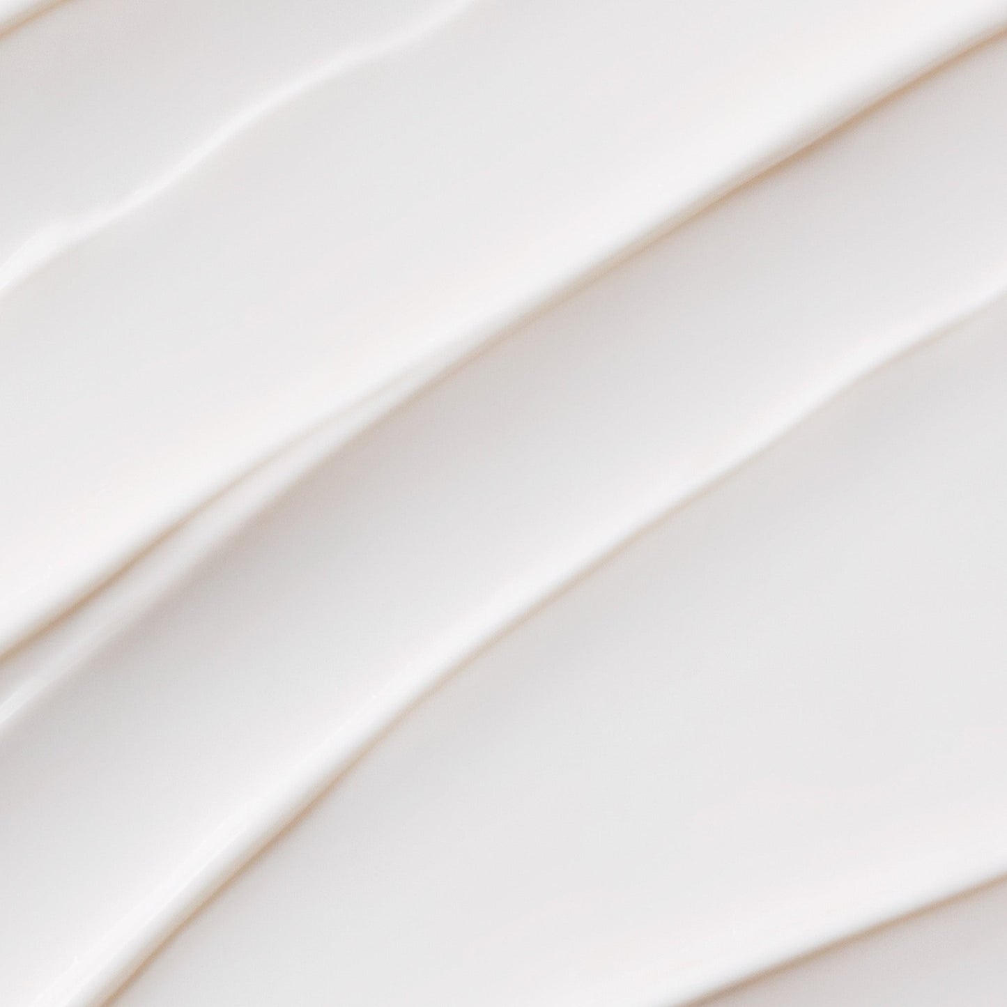 Close-up of smooth, creamy white substance in curved strokes creates a soft, textured surface, evoking Dermalogica’s prisma protect spf30—a multitasking moisturiser offering broad spectrum defense.