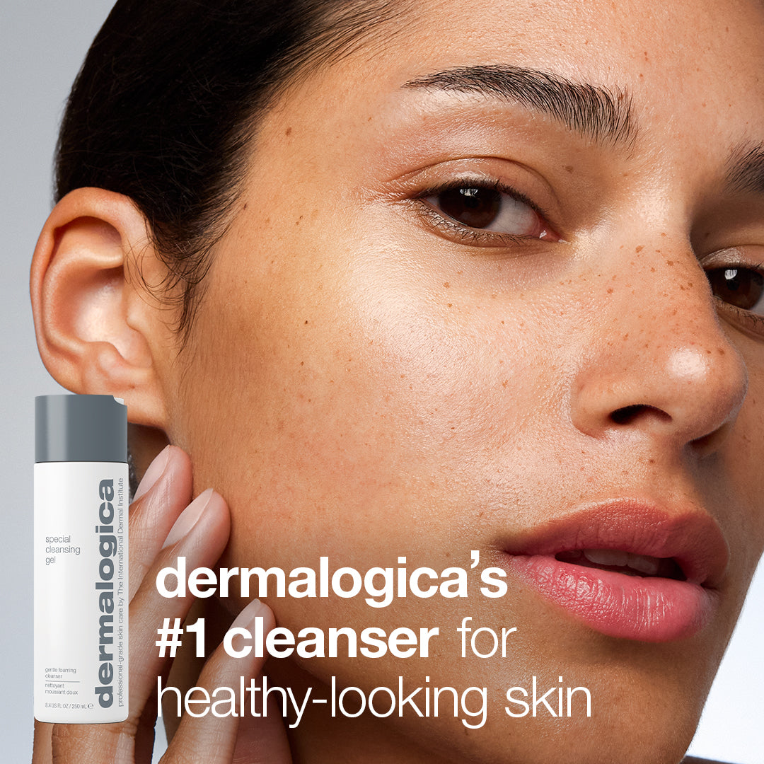 A person with clear skin touches their cheek next to a bottle of cleansing gel from the expert cleanse + glow set, with text that reads Dermalogica’s #1 cleanser for healthy-looking skin.