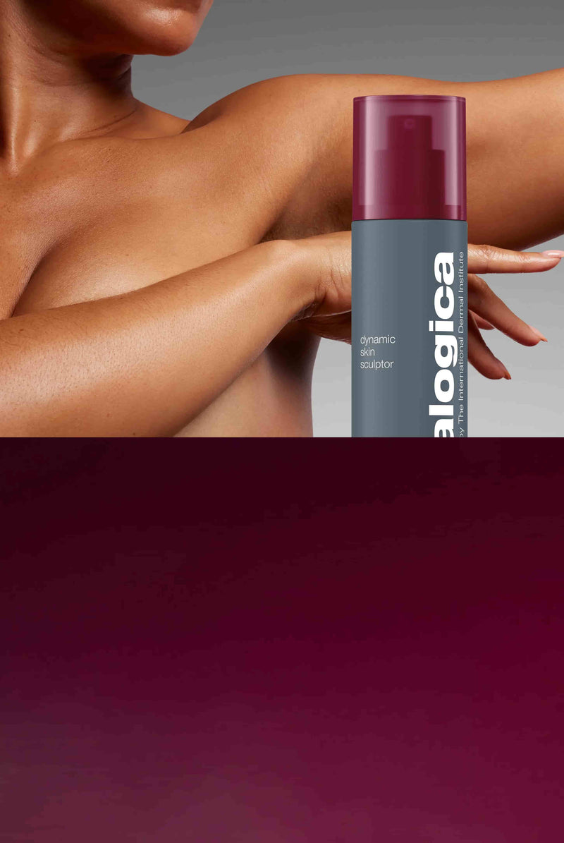A person with medium brown skin poses with an arm raised, holding a bottle of Dermalogica Dynamic Skin Sculptor lotion. The product label and maroon cap are clearly visible. The background is softly gradient.