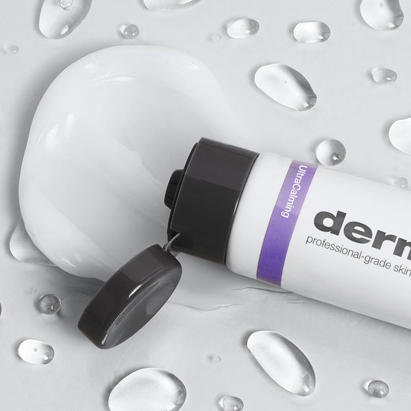 Dermalogica calm water gel, in a white bottle with a purple label and open cap, dispenses hydrating gel onto a surface with water droplets—ideal for moisturizing dry skin.