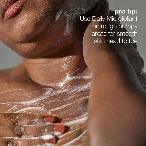 A close-up of a person applying Dermalogica daily microfoliant to their upper chest and shoulder. Overlaid text: Pro tip—use this exfoliating powder on rough, bumpy areas for smooth, brighter skin from head to toe.