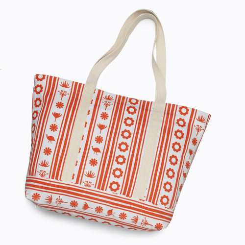 The gift | Sindiso Khumalo tote bag from Dermalogica South Africa features cream handles and a white background adorned with red horizontal and vertical lines, as well as patterns of flowers, leaves, and birds.