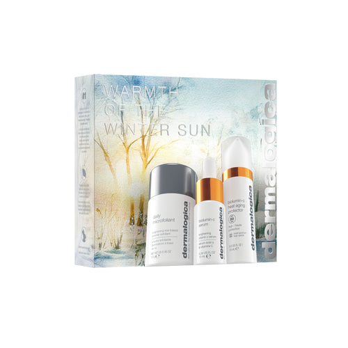 Three Dermalogica South Africa products—Daily Microfoliant, Biolumin-C Serum, and Biolumin-C Gel Moisturizer—are displayed in front of the "gift | warmth of the winter sun" box with a winter scene.