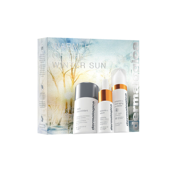 Three Dermalogica South Africa products—Daily Microfoliant, Biolumin-C Serum, and Biolumin-C Gel Moisturizer—are displayed in front of the "gift | warmth of the winter sun" box with a winter scene.