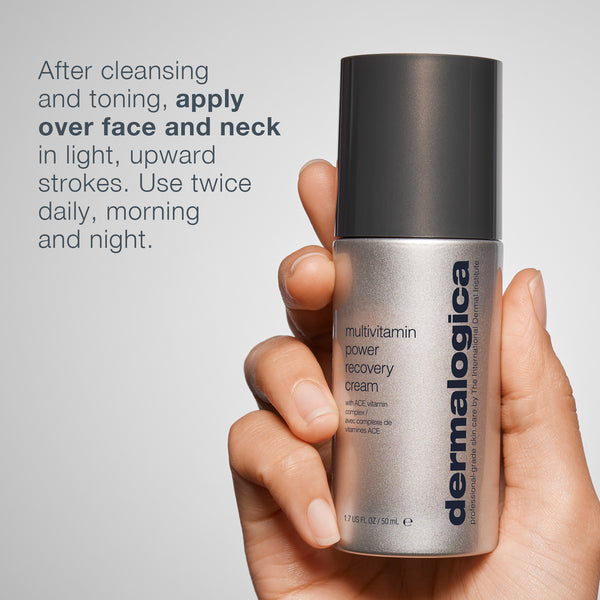 A hand holds a bottle of Dermalogica South Africa multivitamin power recovery cream. The label advises applying to face and neck after cleansing and toning, using light upward strokes, twice daily.