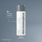 A white bottle of Dermalogica Oil to Foam Total Cleanser with a grey cap is shown on a grey background. Text highlights that it gently cleanses skin, removing oil and impurities in one step.