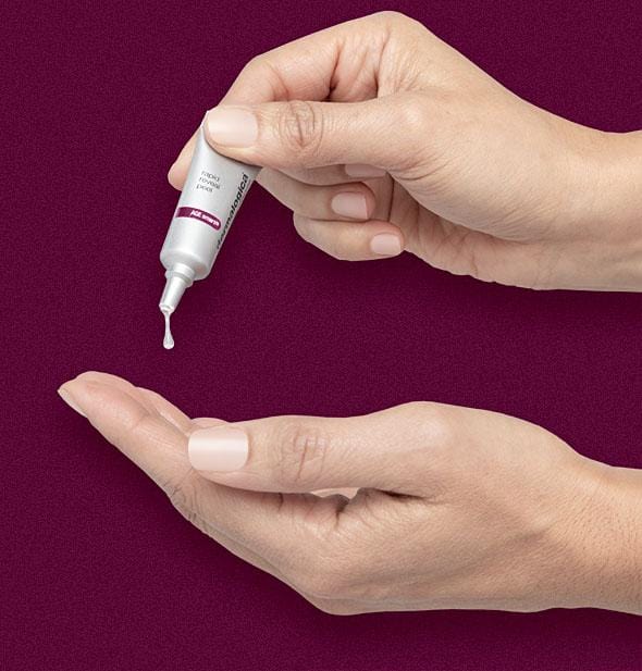 A hand squeezes a small amount of Dermalogica rapid reveal peel from a silver tube onto another palm, set against a burgundy background.