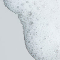 A white Dermalogica clearing skin wash bottle with a gray cap and teal accent band displays the brand name in large gray letters. This foaming cleanser contains salicylic acid to help clear and prevent breakouts.