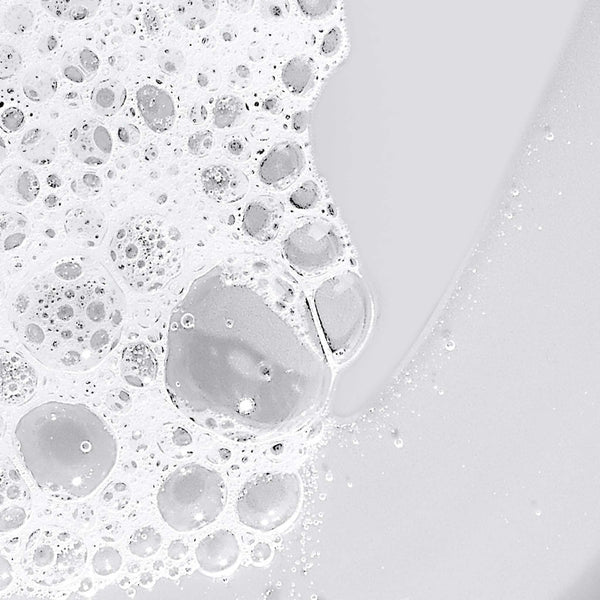 Close-up image of soap bubbles clustered on a smooth, light gray surface, evoking the rich lather of Dermalogica conditioning body wash infused with essential oils for nourishing skin.